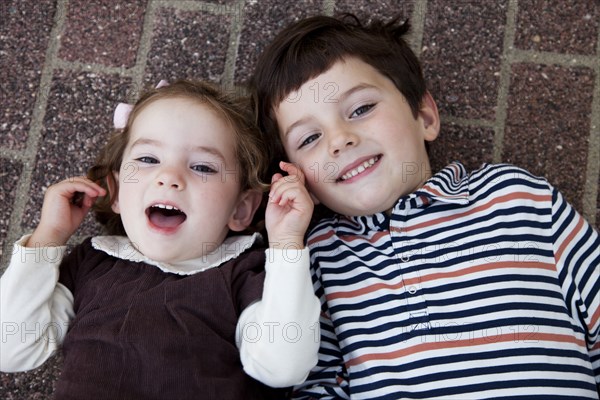 Smiling Boy and Girl Laying on Ground Portrait