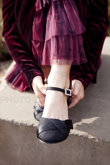 Girl in Red Dress Putting on Black Ballet Shoe, Close-up