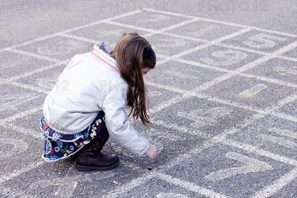 Girl Rolling Acorn on Hopscotch Court