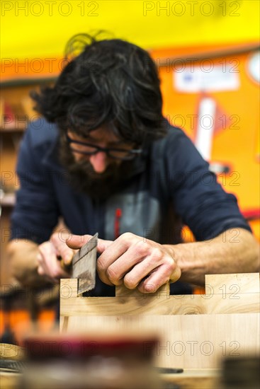 Woodworker Using Hand Saw in Workshop