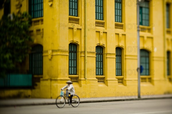 Bicyclist Passing Yellow Building, Ba Dinh Square, Hanoi, Vietnam
