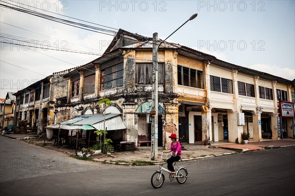 Young Girl Riding Bicycle Past Old French Villas, Kampot, Cambodia