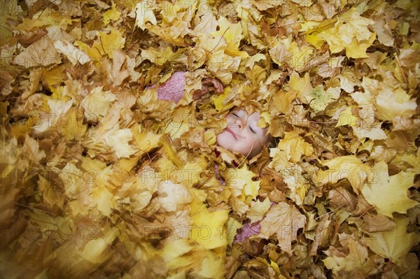 Girl Covered in a Pile of Autumn Leaves