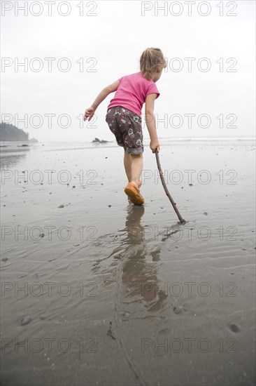 Young Girl Playing with Stick on Beach