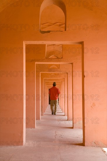 Man Walking Through Series of Orange Doorways