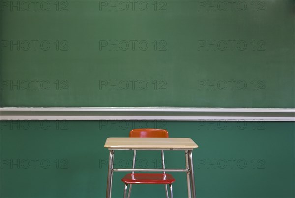 Empty Desk by Classroom Chalkboard