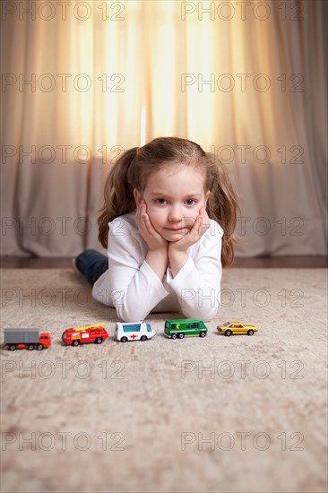 Girl Portrait on Floor with Toy Cars and Trucks