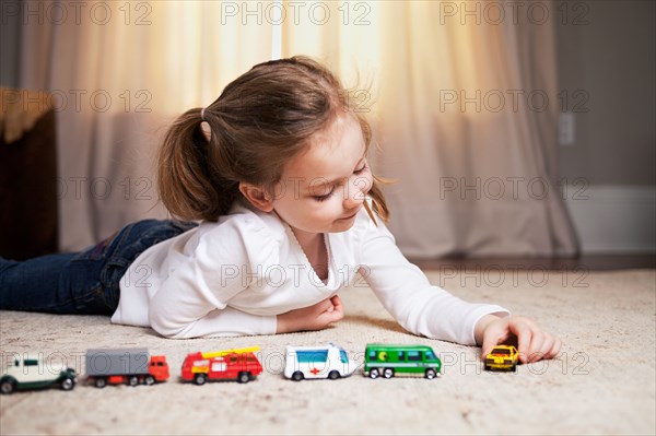 Girl Playing on Floor with Miniature Cars and Trucks