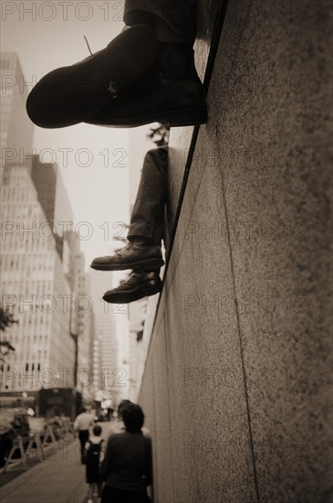 Legs and Shoes Dangling From Edge of Wall, New York City, USA