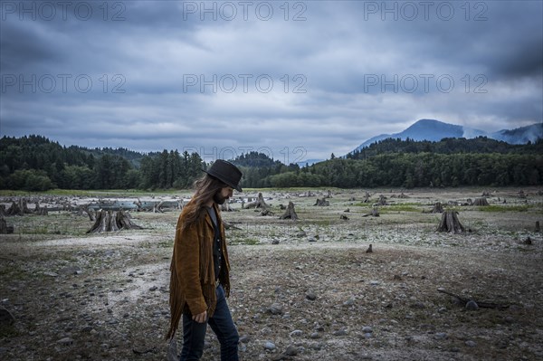 Young Adult Man Walking Across Dried Up Lake with Wildfire Smoke in Background