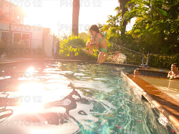 Young Girl Jumping in Pool with Sun Flare