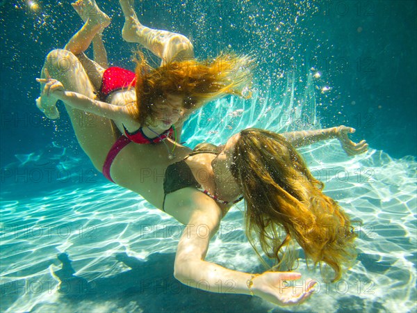 Mother and Daughter Playing Underwater in Pool