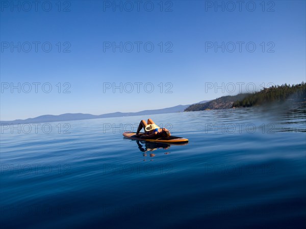 Woman Laying Down on Paddleboard on Lake 2