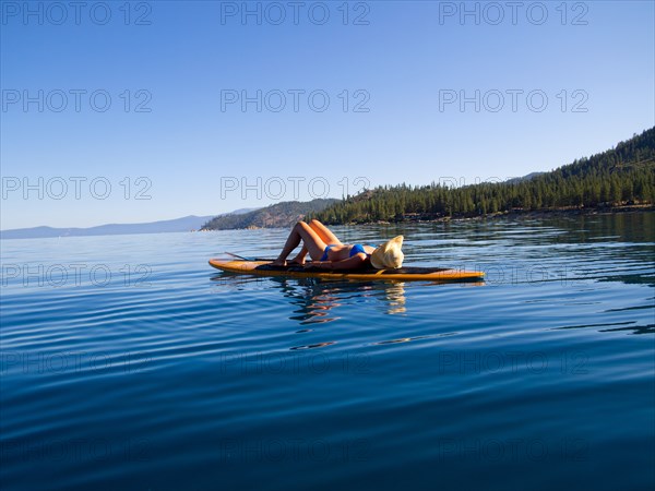 Woman Laying Down on Paddleboard on Lake 3