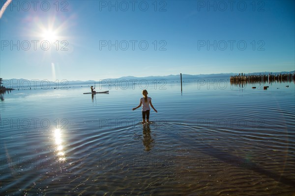 Young Girl Wading out to Woman on Paddle Board, Lake Tahoe, Nevada, USA