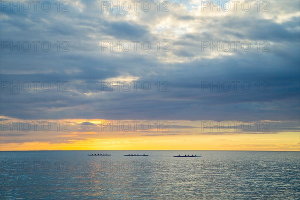 Three Outrigger Canoe Clubs Paddling at Sunset, Hawaii, USA