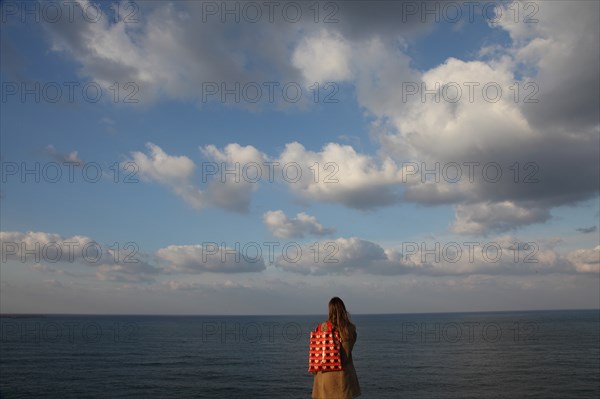 Young Woman on Beach Looking at Horizon, Rear View