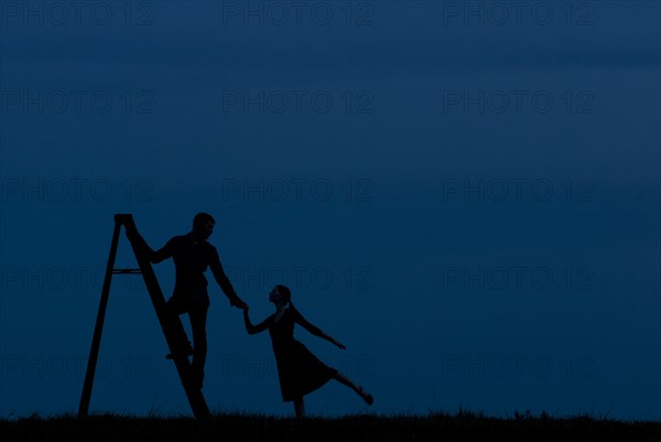 Man Standing on Ladder While Holding Woman's Hand, Silhouette