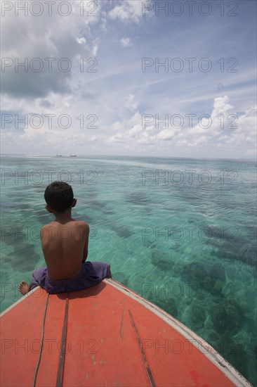 Young Boy Sitting at Front of Boat and Looking out to Sea, Borneo