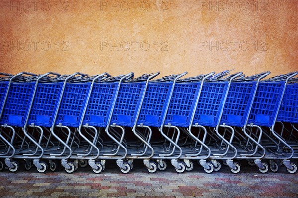 Line of Blue Shopping Carts Against Colorful Wall