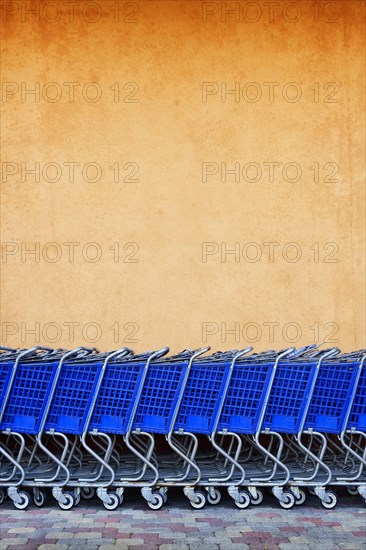 Line of Blue Shopping Carts Against Colorful Wall