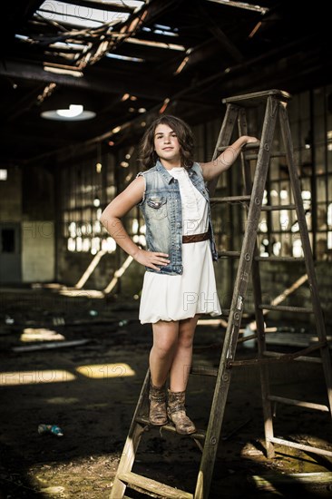 Girl Standing on Ladder in Abandoned Warehouse