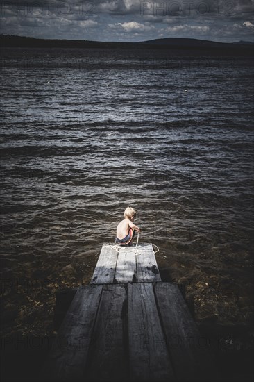 Young boy Playing With Rope at End of Dock on Lake