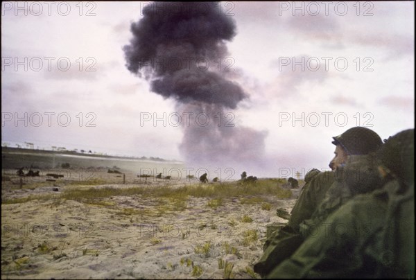 U.S. Soldiers Protect themselves from Enemy Fire as 88mm Shell from German Howitzer Explodes in Background, Utah Beach, Normandy, France, June 1944