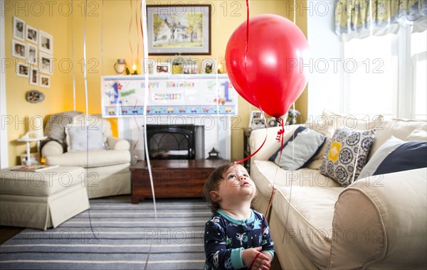 Infant Boy Looking up at Red Balloon in Living Room