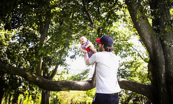 Father Holding up Infant Son in Park