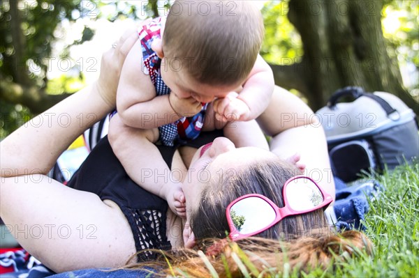 Mother Holding Infant Son While Laying in Grass