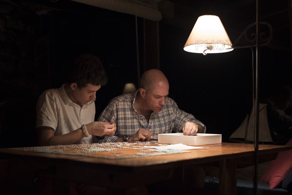 Father and Son Doing Jigsaw Puzzle at Night