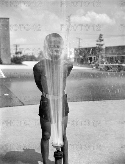 Young Boy Playing in the Community Sprayer,  Frederick Douglass Housing Project, Anacostia Neighborhood, Washington DC, USA, Photograph by Gordon Parks, June 1942