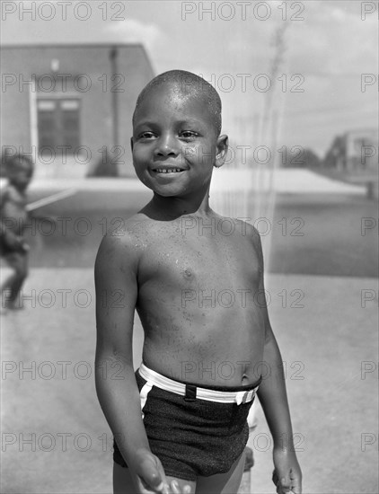 Young Boy Cooling off in the Community Sprayer, Frederick Douglass Housing Project, Anacostia Neighborhood, Washington DC, USA, Photograph by Gordon Parks, June 1942