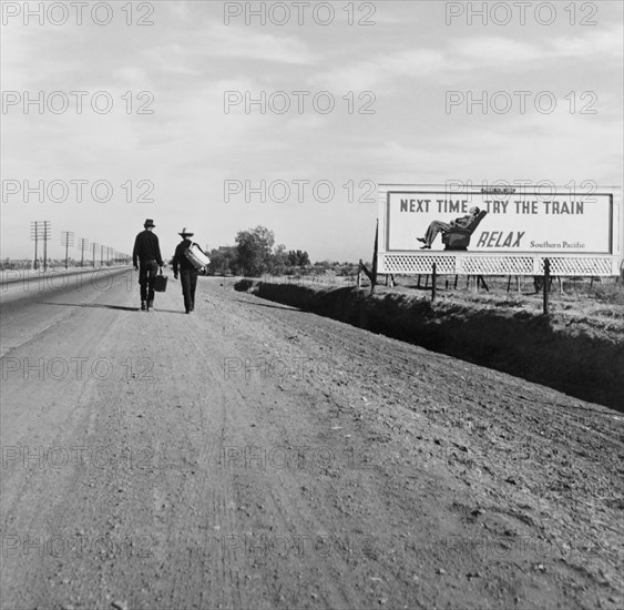 Rear View of Two Men Walking toward Los Angeles, California, USA, on Dirt Road near Billboard that says "Next Time Try the Train. Relax.", Dorothea Lange, U.S. Farm Security Administration, March 1937