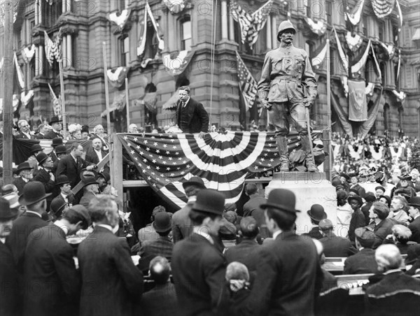 President Theodore Roosevelt speaking to a crowd from a platform next to a statue of Henry Ware Lawton, Indianapolis, Indiana, USA, 1907