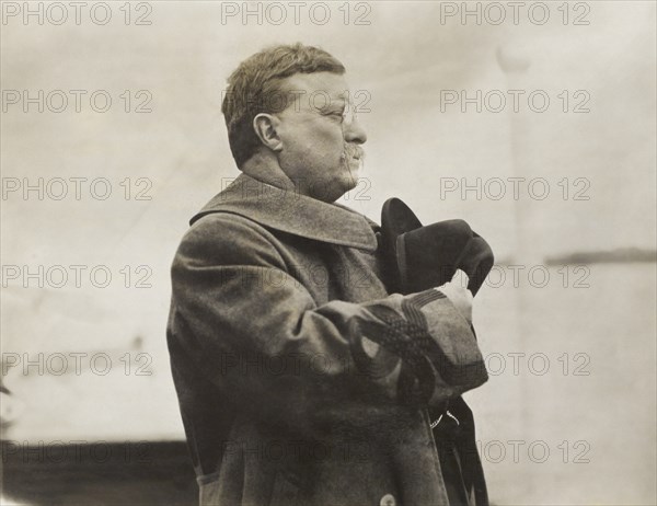 Theodore Roosevelt, half-length portrait, facing right holding hat over heart, Saluting while passing through line of Norwegian Battleships, on Board Queen Maud, during Visit to Norway, American Press Association, May 1910