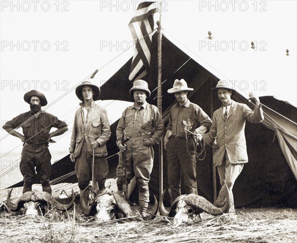 Former U.S. President Theodore Roosevelt (center) with L-R: Hunter R. J. Cunninghame, son Kermit Roosevelt,  Edmund Heller, and Hugh H. Heatley, Full-Length Portrait standing with African Buffalo Skulls while on Extended African Safari, Smithsonian-Roosevelt African Expedition, Kenya, Charles Scribner's Sons, July 1909