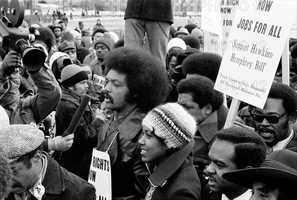 Jesse Jackson speaking into a microphone, surrounded by marchers carrying signs advocating support for the Hawkins-Humphrey Bill for full employment, Washington, D.C., USA, photograph by Thomas J. O'Halloran, January 1975
