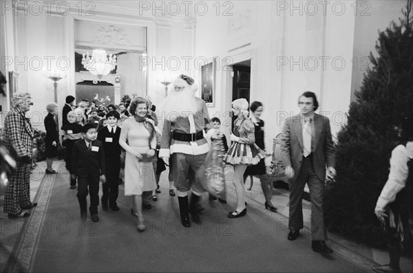 First Lady Betty Ford, Santa Claus, and clowns lead a procession of Diplomatic Corps children at a White House Christmas party, Washington, D.C., USA, photograph by Thomas J. O'Halloran, December 16, 1975