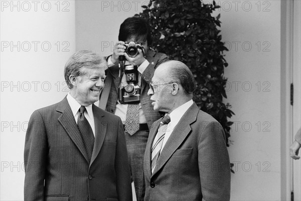 U.S. President Jimmy Carter and Israeli Prime Minister Menachem Begin talk at the White House as photographer adjusts his camera in background, Washington, D.C., USA, photographer Thomas J. O'Halloran, Marion S. Trikosko, April 1980