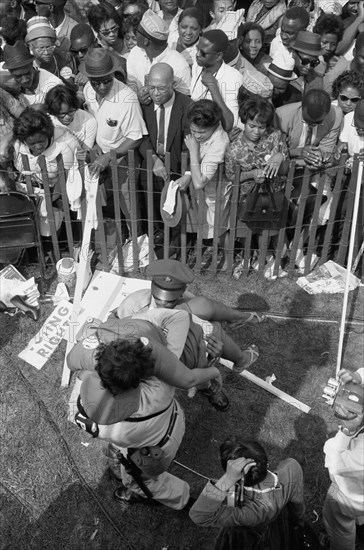 Crowd of African Americans behind a storm fence with police carrying a woman on the other side during March on Washington for Jobs and Freedom, Washington, D.C. USA, photograph by Marion S. Trikosko, August 28, 1963