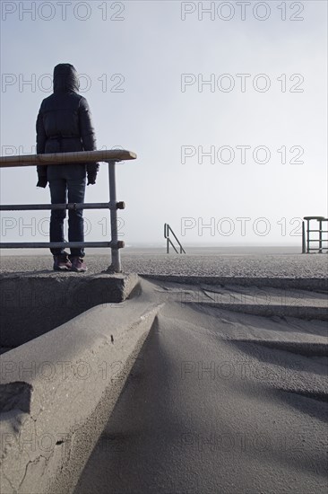 Rear View of Hooded Person Standing on Empty Beach