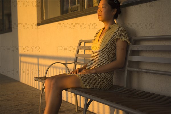 Portrait of Contemplative Mid-Adult Woman sitting on Bench with Shadows