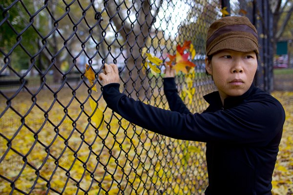 Half-Length Portrait of Woman Looking over her Shoulder While Standing at Fence