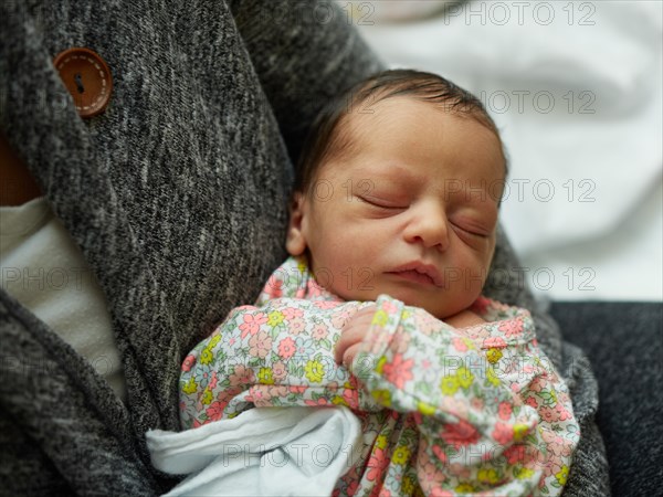 Newborn Baby Girl Sleeping in Mother's Arms in Hospital