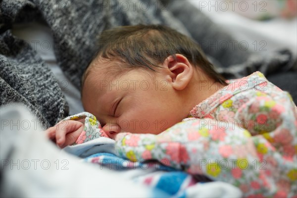 Newborn Baby Girl Sleeping in Mother's Arms in Hospital