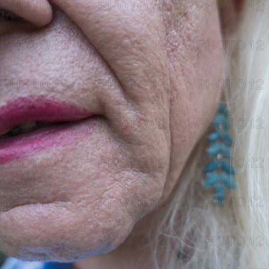 Close-Up Portrait of Man's Lips with Pink Lipstick and Ear with Blue Earring