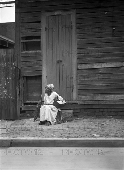 Female Praline Vendor sitting on Steps holding a Basket