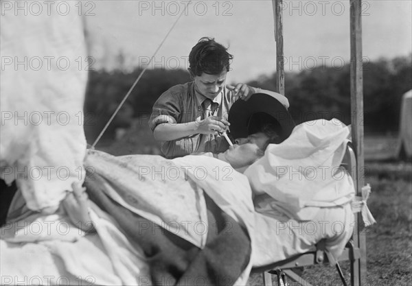 American Red Cross Boy Scout lighting Cigarette for Soldier unable to help himself in Hospital near Paris